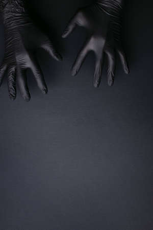 Hands in black gloves on black background. Treat or trick.の写真素材