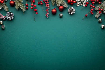 Christmas border with classic decorations. Fir branches, red balls, jingle bells on green background.の写真素材