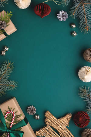 Vertical Christmas frame with gift boxes, paper decorations and spruce branches on turquoise background. Holiday background in earth colours.の写真素材