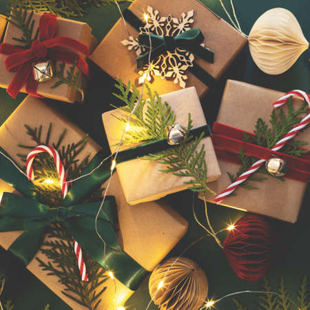 Many Christmas gift boxes tied velvet ribbons with paper decorations in garland lights.の写真素材