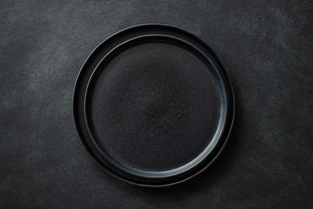 Empty black plates on black stone table. Top view.の写真素材