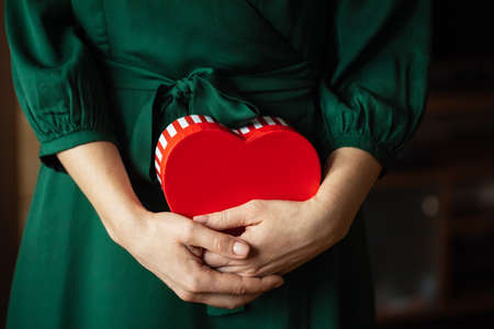 Womans Hands holding a red heart gift box. Card for Valentines Day.の写真素材