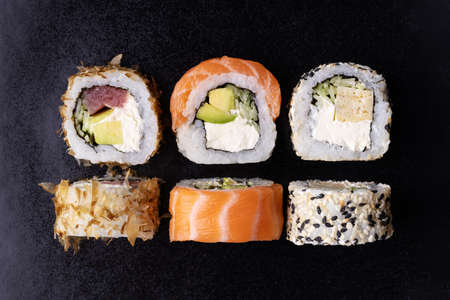 Sushi rolls set with avocado, cheese, salmon and tuna on black background. Top view.の写真素材
