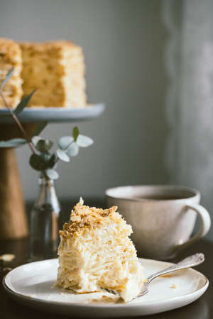 Slice of multilayers cake Napoleon on the plate and cup of tea.の写真素材