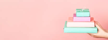 Kids hands holding four gift boxes in pastel color.