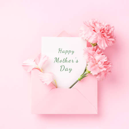 Happy Mothers Day card in pink envelope with carnations on pink background.の写真素材