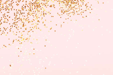Scattering of golden confetti on pink background.の写真素材