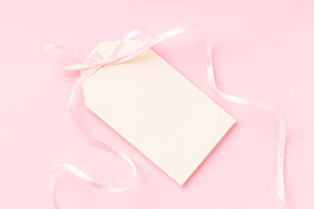 Blank price tag with pink ribbon bow on pink background.の写真素材