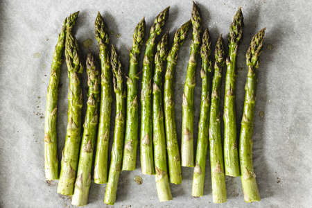 Fresh asparagus with olive oiland pepper on baking paper, top view.の写真素材