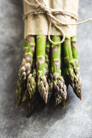Bunch of fresh asparagus tied rope on gray background.の写真素材