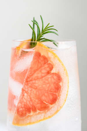 Close up of glass of cold water with grapefruit and rosemary garnish.の写真素材