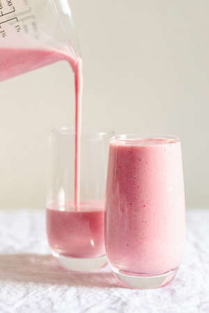 Strawberry smoothie pouring in the glass.の写真素材