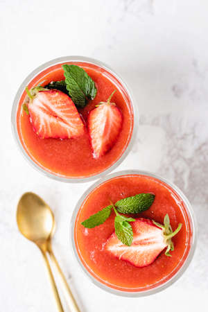 Top view on panna cotta in glasses with strawberry sauce and mint.の写真素材
