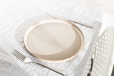 Empty plate on white linen tablecloth.