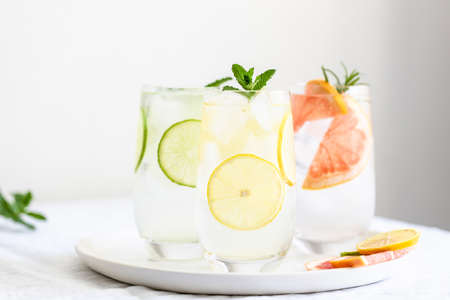 Three glasses with cold citrus lemonade with mint garnish on plate.の写真素材
