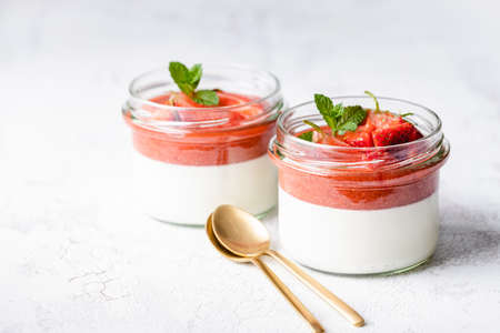 Panna cotta in glass jars with strawberry sauce and mint.の写真素材