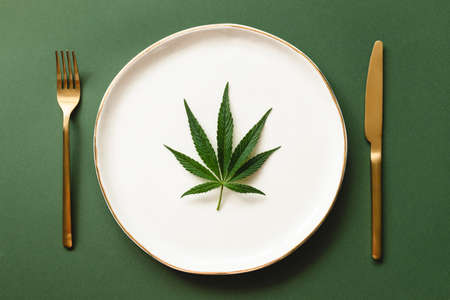 Leaf of cannabis on white plate with golden rim.の写真素材