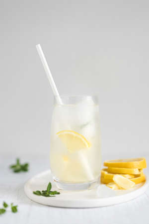 Glass of lemonade with paper straw on white plate.の写真素材