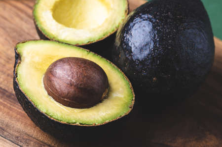 Halves of avocado Hass and whole avocado on wooden background.の写真素材