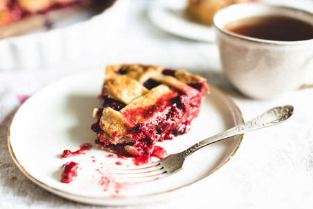 Piece of classic raspberry pie on plate with fork.