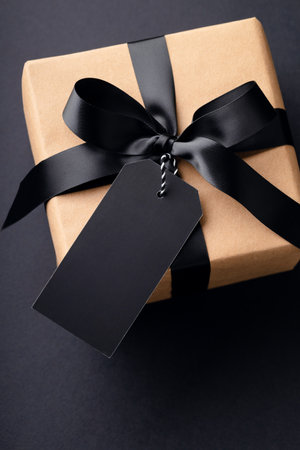Overhead view on gift box with black bow and tag on black background.の写真素材