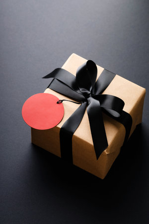 Gift box with black bow and red price tag on black background.の写真素材
