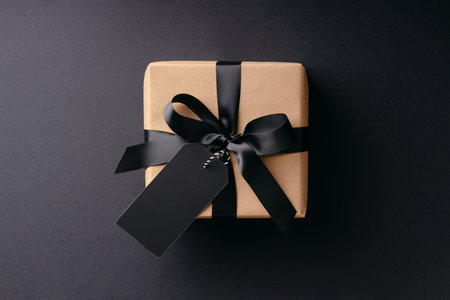 Gift box with black bow and price tag on black background.の写真素材