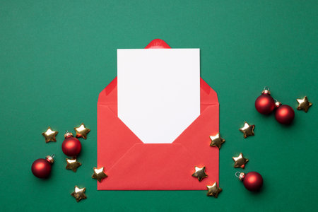Mock-up with empty card in red envelope on green background with Christmas decorations.の写真素材