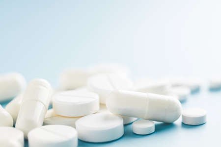 Different shapes white pills on blue background.の写真素材