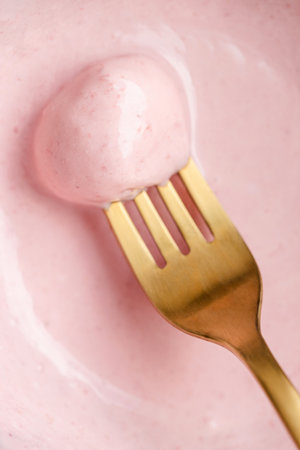 Conceptual closeup view of sweet cheese ball on golden fork with pink berry sauce.の写真素材