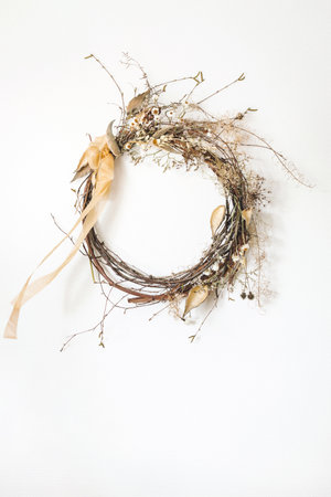 Aesthetic interior wreath made of dry flowers, herbs and silk ribbon hang on white wall.の写真素材