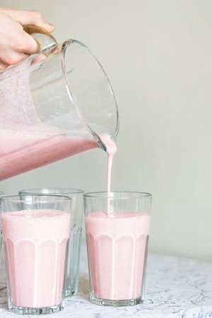 Strawberry smoothie or milkshake pouring in the glass. Summer healthy drinks recipe.の写真素材