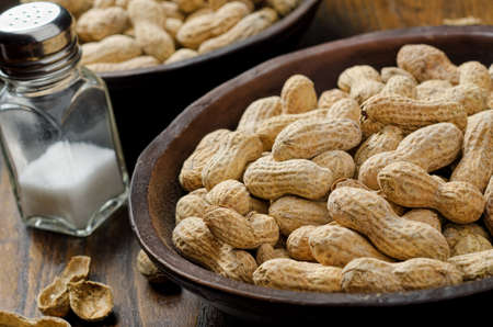 A bowl of whole peanuts in the shell with table salt.の写真素材