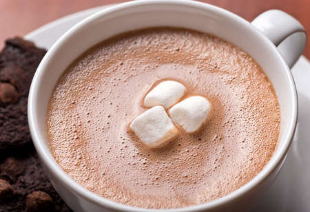 Close up of a fresh creamy cup of hot chocolate with marshmallows and chocolate chip cookies.
