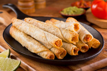 A platter of delicious chicken taquitos with salsa guacamole and lime.の写真素材