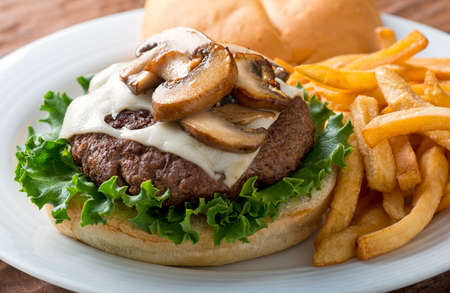 A delicious hamburger topped with swiss cheese and fried mushrooms on a kaiser.の写真素材