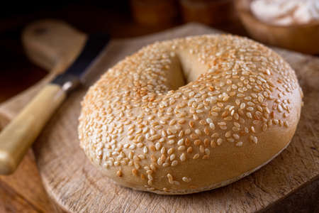 A delicious sesame seed bagel on a rustic wooden table top.の写真素材