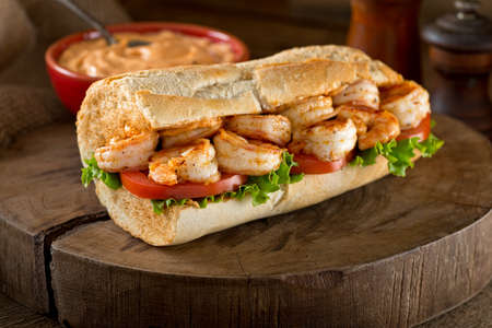 A delicious home made grilled shrimp Po Boy sandwich on baguette dressed with lettuce, tomato, and remoulade.の写真素材