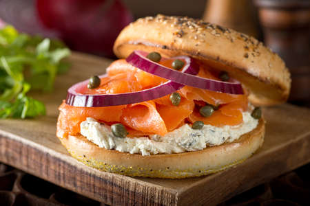 A delicious toasted bagel with smoked salmon, cream cheese, capers, and red onion.の写真素材