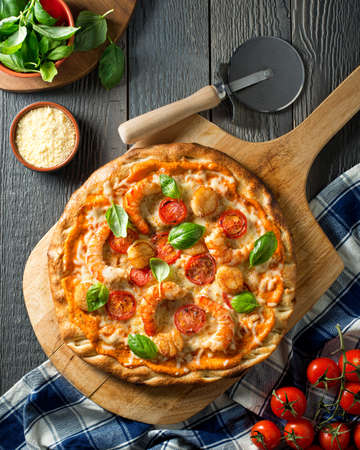 A delicious seafood pizza with shrimps, scallops, tomato, and basil with zesty red pepper sauce.の写真素材