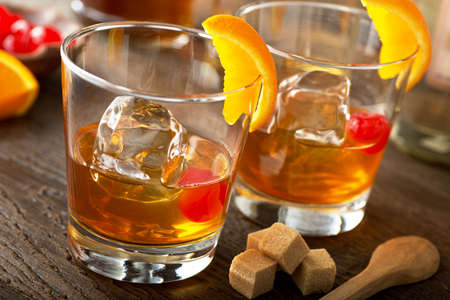 Delicious old fashioned cocktails with bourbon, bitters, sugar, orange, and maraschino cherry.の写真素材