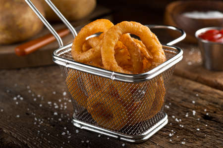 Crispy delicious onion rings in a fryer basket.
