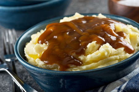 A bowl of delicious mashed potatoes with gravy and melted butter.の写真素材