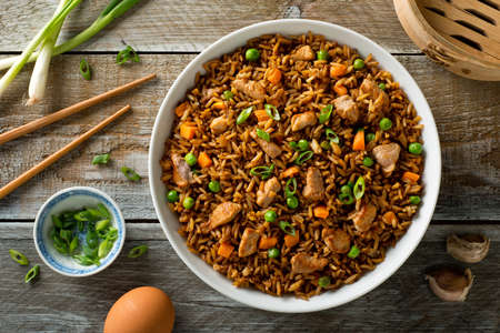 Delicious pork fried rice with egg, carrot, green peas, garlic and green onion.の写真素材