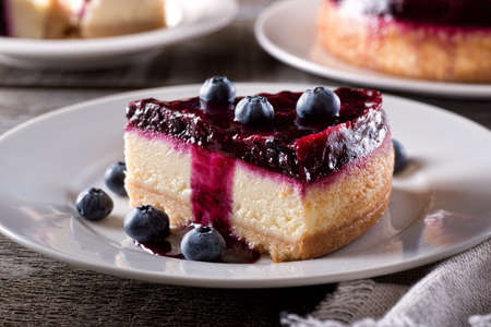 A slice of delicious blueberry cheesecake with fresh blueberries on a rustic wood table top.の写真素材