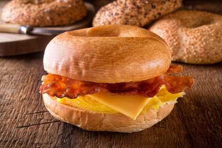 A delicious toasted breakfast bagel with egg, bacon and cheese.の写真素材