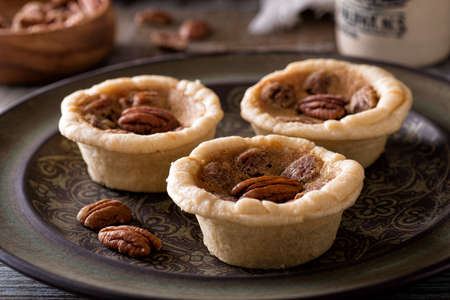 Delicious homemade mini pecan butter tarts on a rustic table top.の写真素材