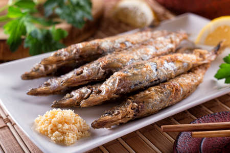 A plate of delicious grilled shishamo with roe and lemon and parsley garnish.