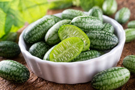 Freshly harvested cucamelons in bowl on a rustic wood table.の写真素材