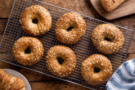 Freshly baked whole grain bagels cooling on a rack.